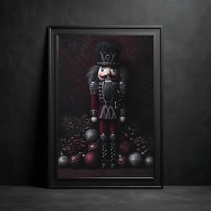 May include: Framed print of a nutcracker soldier in a red and black uniform, with a black hat and gray hair. The print is surrounded by Christmas ornaments, pinecones, and red and silver baubles.