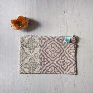 May include: A beige zippered pouch with a brown and white geometric pattern. The pouch has a small, round, teal label with the word "yogalife" printed on it.