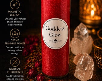 May include: A tall, red candle in a glass jar, labeled "Goddess Glow", is lit with a flame. The candle is surrounded by crystals and other decorative elements. The candle is hand-crafted and made with herbs, oils, and intention.