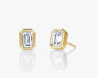 May include: A pair of gold earrings with emerald cut diamonds set in a bezel setting.