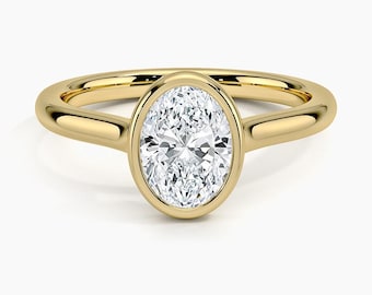 May include: A gold engagement ring with a bezel-set oval diamond.