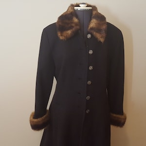 Peut inclure: Un long manteau noir avec un col et des poignets en fourrure brune. Le manteau a une fermeture à boutons et une silhouette ajustée.
