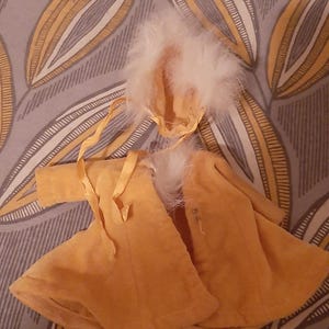 May include: A yellow hooded baby doll coat with white fur trim. The coat has a ribbon tie and is made of a soft, plush fabric.