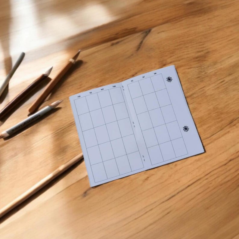 Pode incluir: Um planejador branco, em branco, quadriculado com um pequeno desenho de flor no canto superior direito. O planejador est&aacute; aberto para uma semana.