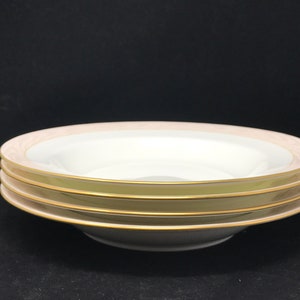 May include: Three white soup bowls with a gold rim and a pale pink band. The bowls are stacked on top of each other.