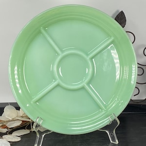 Może przedstawiać: Okrągły, jasnozielony talerz do serwowania z podziałem. Talerz ma centralny okrągły obszar i cztery sekcje w kształcie ciasta. Talerz jest wykonany z błyszczącego materiału i jest prezentowany na przezroczystym stojaku.