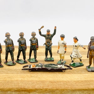 以下が含まれることがあります： 担架と負傷した兵士を含む、ヴィンテージの玩具兵士10体セット。兵士は塗装された鉛製で、さまざまなポーズと制服をしています。セットには、看護師、医師、戦闘装備の兵士が複数含まれています。