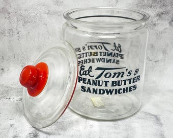 Frasco de vidrio vintage de 14" para sándwiches de mantequilla de maní Tom's de 5 centavos con tapa roja Tom's.
