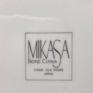 May include: A white Mikasa bone china plate with the text "Mikasa Bone China CAGO1 Silk Moire Japan" printed on the bottom.