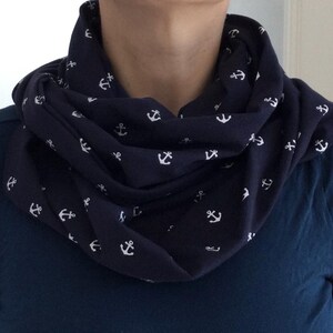 Könnte beinhalten: Ein marineblauer Infinity-Schal mit einem weißen Ankerdruck. Der Schal ist aus einem weichen, bequemen Stoff gefertigt und perfekt, um jedem Outfit einen Hauch von nautischem Stil zu verleihen.