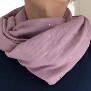 Könnte beinhalten: Ein weicher, mauvefarbener Schal mit goldenen Punkten. Der Schal ist aus einem leichten Stoff gefertigt und zu einer Schleife gefaltet.