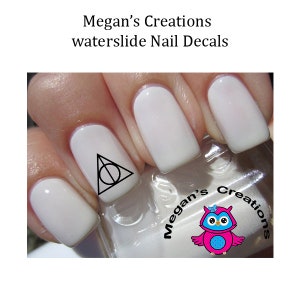May include: White fingernails with a black and white triangle with a circle inside, a nail polish bottle with a pink owl logo and the text "Megan's Creations" on the label.