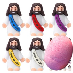 May include: Set of five small figurines of Jesus with different colored sashes that say "Jesus loves you". The figurines are standing on a pink and purple Easter egg.