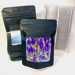 Peut inclure: Une pile de sachets en plastique noir debout avec une fen&ecirc;tre transparente, un sachet est rempli de fleurs violettes s&eacute;ch&eacute;es.