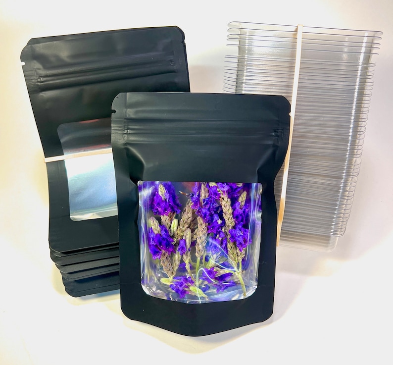 Peut inclure: Une pile de sachets en plastique noir debout avec une fen&ecirc;tre transparente, un sachet est rempli de fleurs violettes s&eacute;ch&eacute;es.