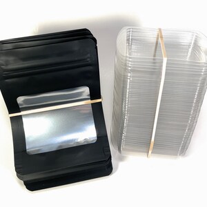 Peut inclure: Une pile de sachets en plastique noir debout avec une fen&ecirc;tre transparente et une pile de contenants en plastique transparent.