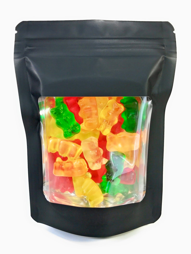 Peut inclure: Un sac refermable noir avec une fen&ecirc;tre transparente montrant une vari&eacute;t&eacute; d'oursons en g&eacute;latine rouge, jaune et vert.
