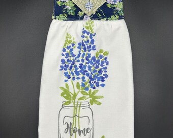 Asciugamano da cucina appeso con scritta "Home" e fiori blu su morbido spugna di cotone bianco.