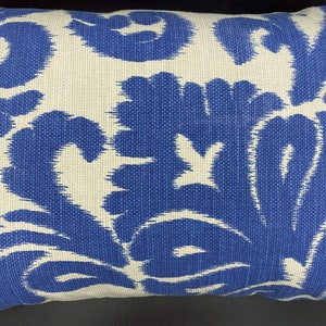 May include: A white throw pillow with a blue floral pattern. The pillow is made of a woven fabric and has a subtle texture.
