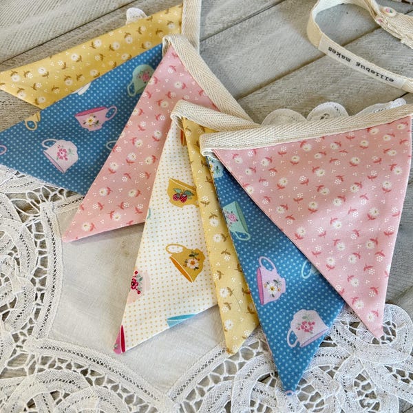 Guirnalda de banderines pequeños de algodón con estampado de amapolas en taza de té de buenos días.