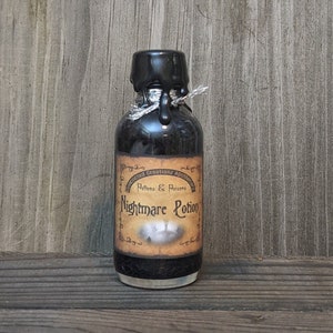 May include: A small, dark glass bottle labeled "Nightmare Potion" with a black wax seal and silver string. The label reads "Boncocted Creationz Apothecary, Potions & Poisons." The bottle is filled with a dark liquid.