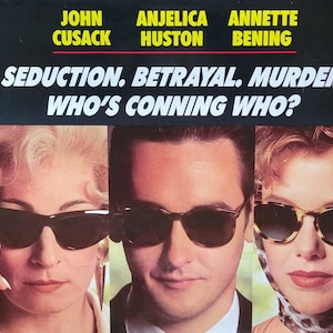 May include: Movie poster featuring John Cusack, Anjelica Huston, and Annette Bening. The poster has a black background with white text that reads "Seduction. Betrayal. Murder. Who's Conning Who?"