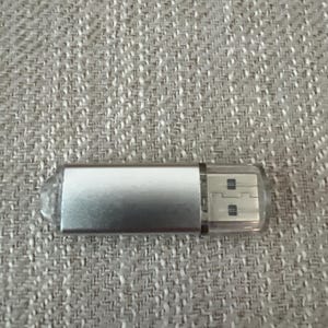 May include: A silver USB flash drive with a clear plastic casing around the USB connector.