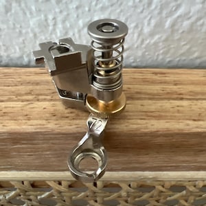 May include: A silver sewing machine foot with a spring and a knob labeled "72".