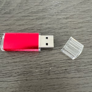 May include: A red USB flash drive with a silver connector and a clear plastic cap.