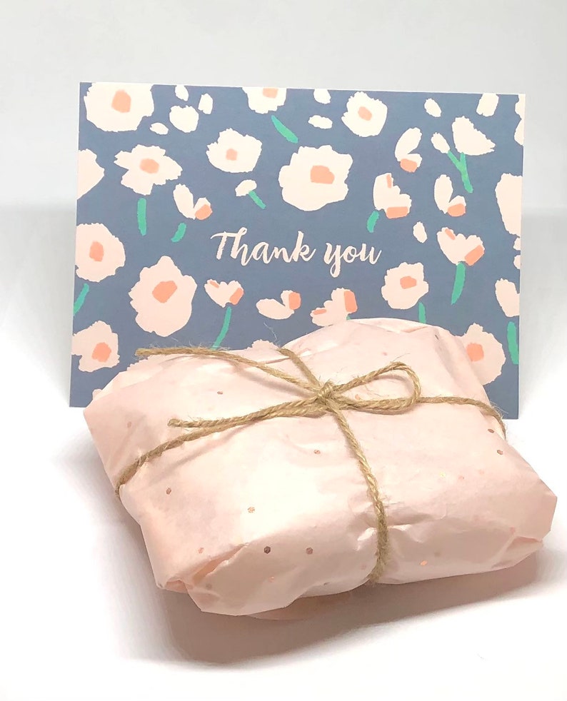 May include: A pink gift box tied with brown twine and a small card with a floral pattern and the text "Thank you".