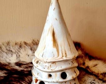 May include: A conical ceramic tree sculpture featuring a white glaze with brown marbled streaks. The structure has three tiered levels with circular cutouts and is topped with a small, solid gold-colored star. The surface has a smooth finish.