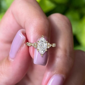 May include: A gold engagement ring featuring a large marquise-shaped diamond and smaller diamonds set in the band.