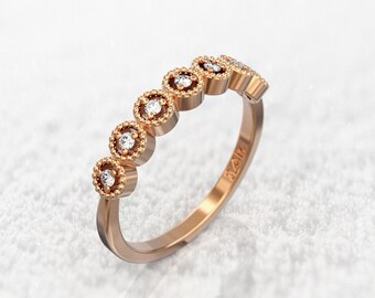 May include: A rose gold band ring with six small round diamonds set in a circle design. The ring has a delicate, feminine look.
