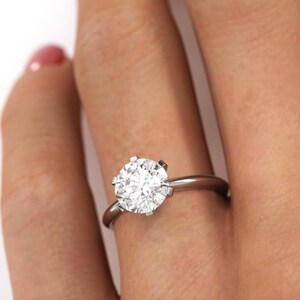 Pu&ograve; includere: Primo piano di una mano che indossa un anello d'argento con un grande diamante rotondo e trasparente.