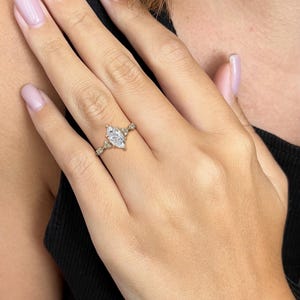 May include: A gold ring featuring a large marquise-shaped diamond and smaller diamonds set in a delicate band.