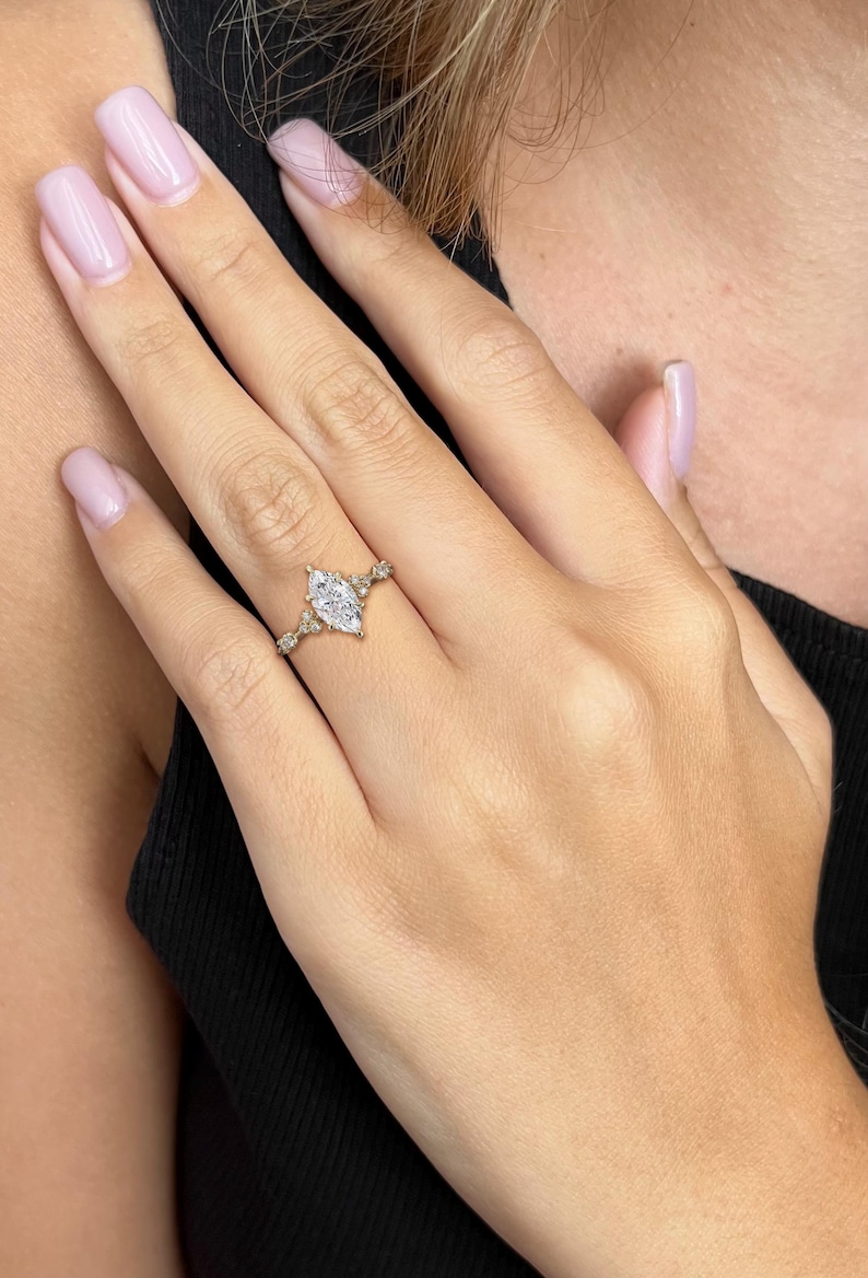 May include: A gold ring featuring a large marquise-shaped diamond and smaller diamonds set in a delicate band.