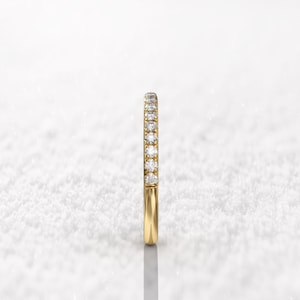 May include: A thin gold band with a row of small diamonds set in a pave setting.