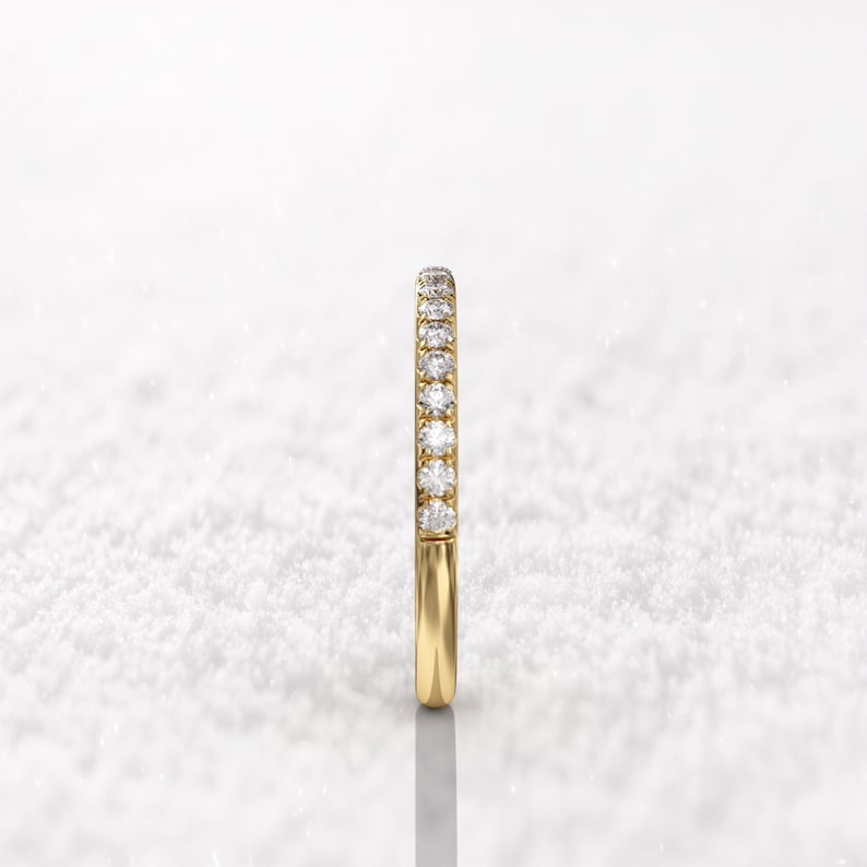 May include: A thin gold band with a row of small diamonds set in a pave setting.