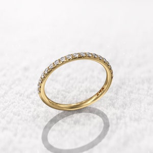 May include: A thin gold band with a row of small diamonds set around the entire ring.
