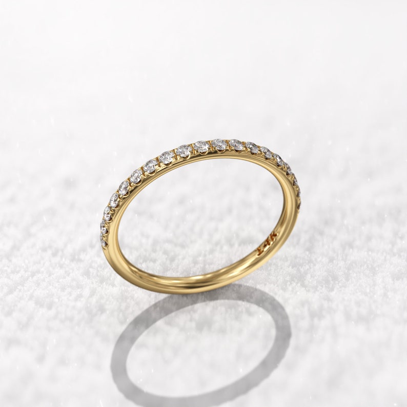 May include: A thin gold band with a row of small diamonds set around the entire ring.