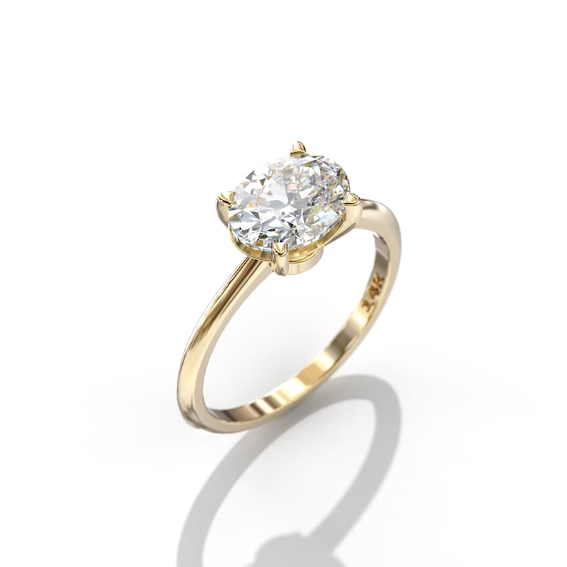 May include: A gold engagement ring with an oval-shaped diamond set in a prong setting. The ring is 14K gold.