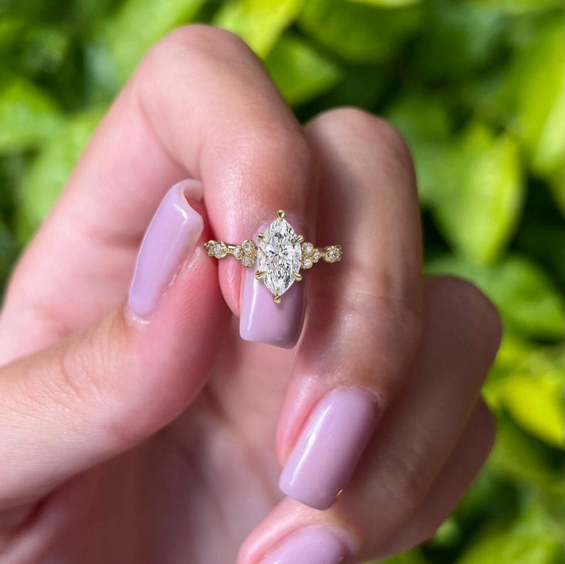 May include: A gold engagement ring featuring a large marquise-shaped diamond and smaller diamonds set in the band.