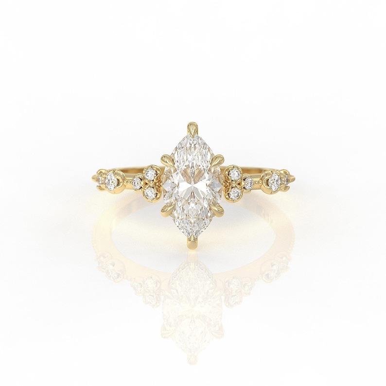 May include: A gold engagement ring featuring a marquise-shaped diamond centre stone and smaller diamonds set in the band.
