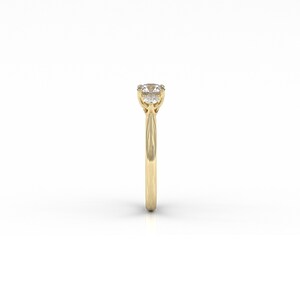 May include: A gold ring with a round, clear gemstone. The ring has a thin band and a four-prong setting. The gemstone is the focal point, set high above the band. The ring is displayed against a white background.