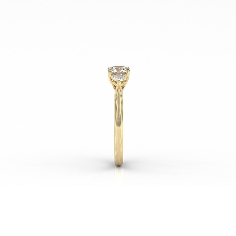 May include: A gold ring with a round, clear gemstone. The ring has a thin band and a four-prong setting. The gemstone is the focal point, set high above the band. The ring is displayed against a white background.