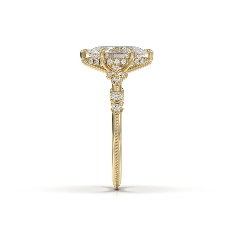 May include: A gold engagement ring featuring a large oval-shaped diamond centre stone, surrounded by a halo of smaller diamonds. The band is also set with smaller diamonds.