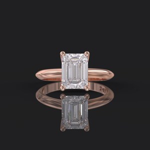 Pu&ograve; includere: Un anello di fidanzamento in oro rosa con un grande diamante taglio smeraldo trasparente.