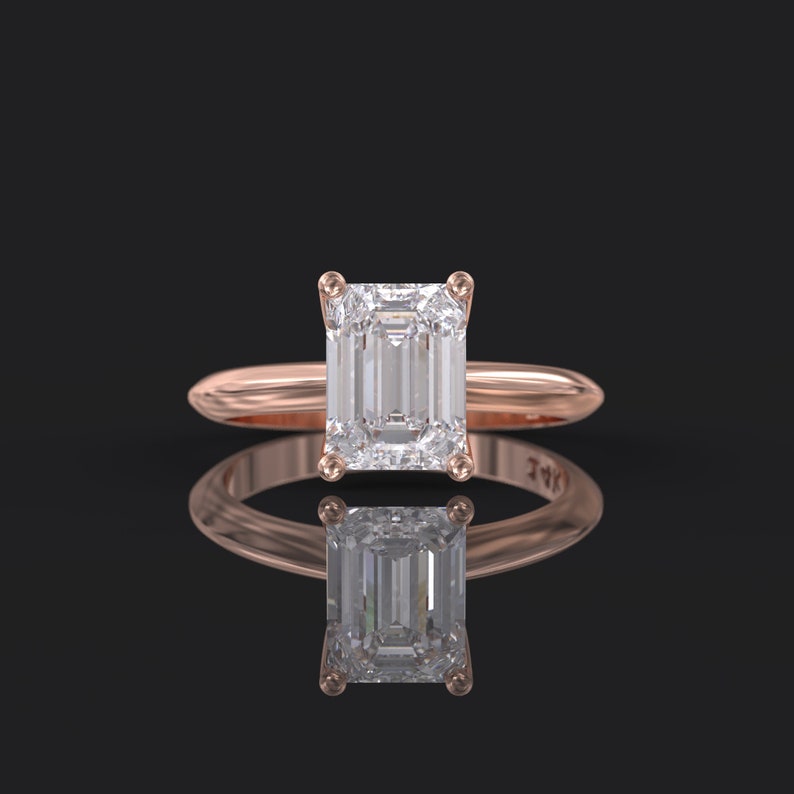 Pu&ograve; includere: Un anello di fidanzamento in oro rosa con un grande diamante taglio smeraldo trasparente.