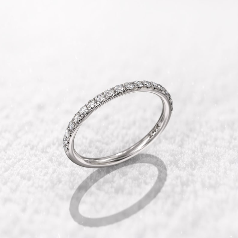 May include: A thin silver band with a row of small diamonds set around the entire ring.