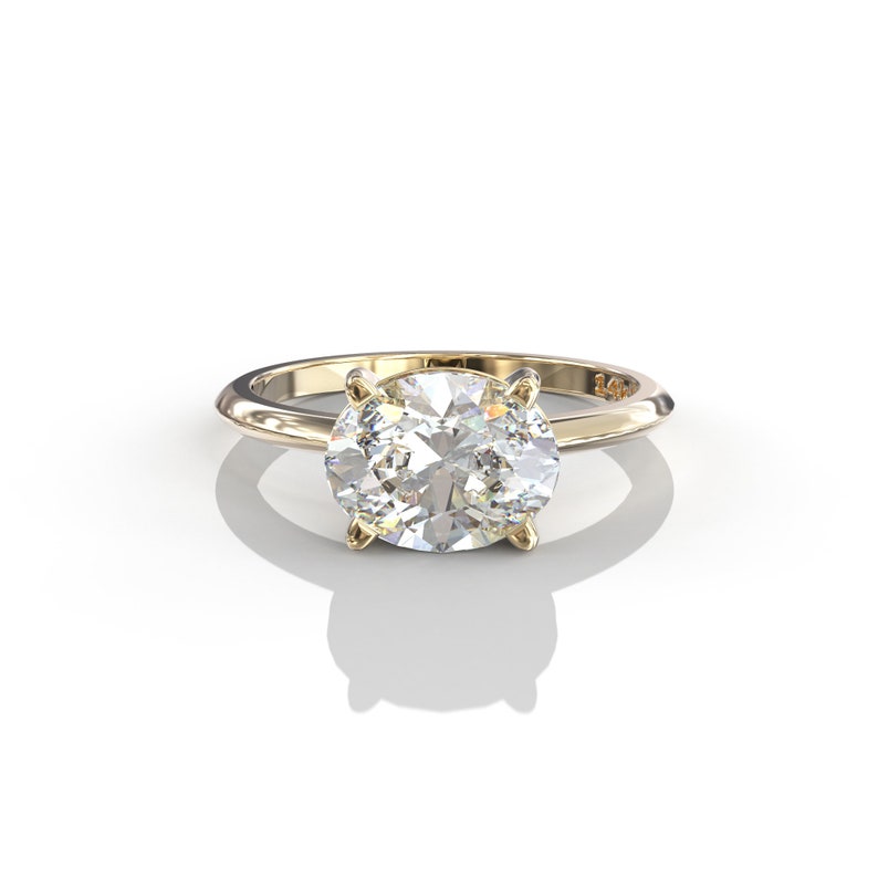 May include: A gold band ring with a large, clear oval-shaped diamond.